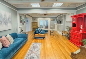 Ein geräumiges Wohnzimmer mit einem blauen Sofa, einem roten Schrank und einem Deckenventilator.