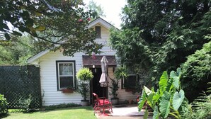 A house with a front yard, a red chair, and a potted plant.