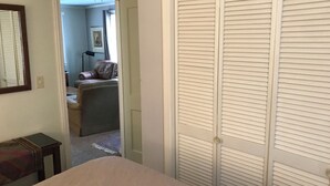 A bedroom with a bed, a closet, and a hallway leading to another room.