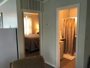 Une chambre d’hôtel avec un lit, un petit bureau, une chaise et une salle de bain avec un rideau de douche.