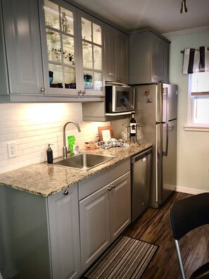 A fully stocked kitchen complete with utensils, glasses, appliances, cookware.