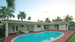 A house with a swimming pool, a covered patio, and palm trees in the background. - Exclusive Home By Traveline Plus (Hollywood)