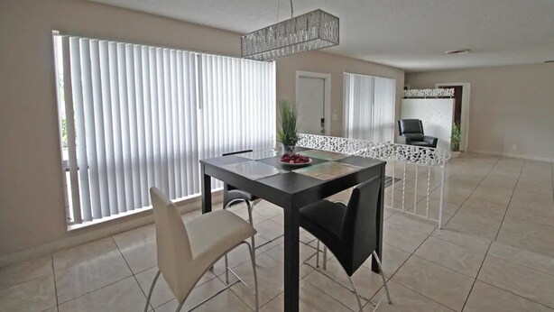 A dining area with a table, chairs, and a chandelier. - Exclusive Home By Traveline Plus (Hollywood)
