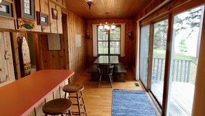 A wooden interior with a bar area, stools, and a large window. - Classic Lake Home (Alden)