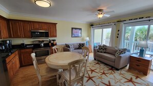 A cozy living room with a dining table, a sofa, and a ceiling fan. - Pet-Friendly Retreat w/ Private Balcony, Just A Short Walk To The Beach (Tybee Island)
