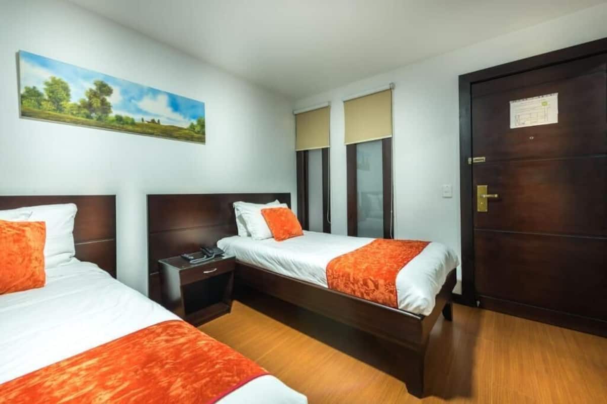 Ein Hotelzimmer mit zwei Betten, einem Nachttisch, einem Bild an der Wand und einer Tür mit einem Hinweis.