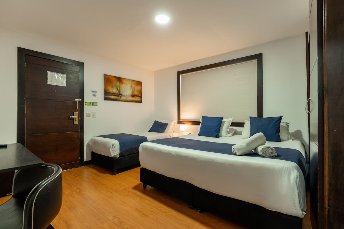 Ein Hotelzimmer mit zwei Einzelbetten, einem Schreibtisch und einem Stuhl.
