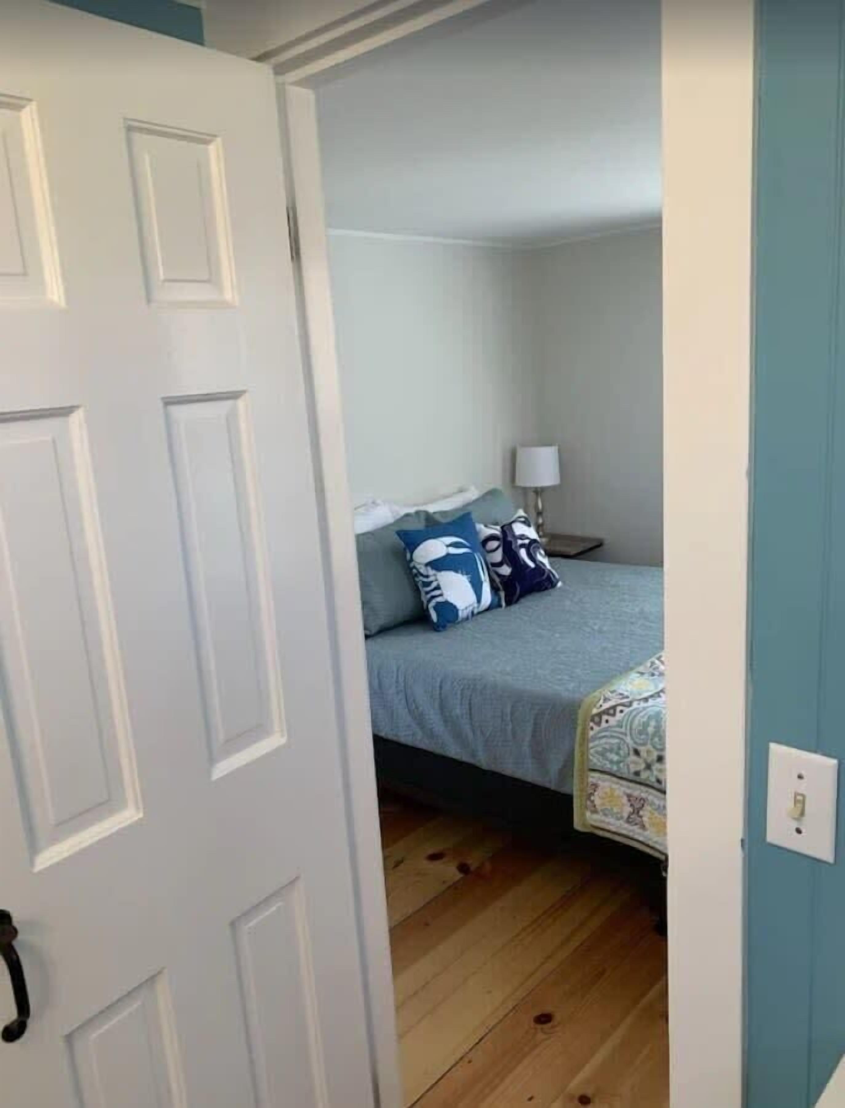 A bedroom with a bed, pillows, a nightstand, and a lamp.