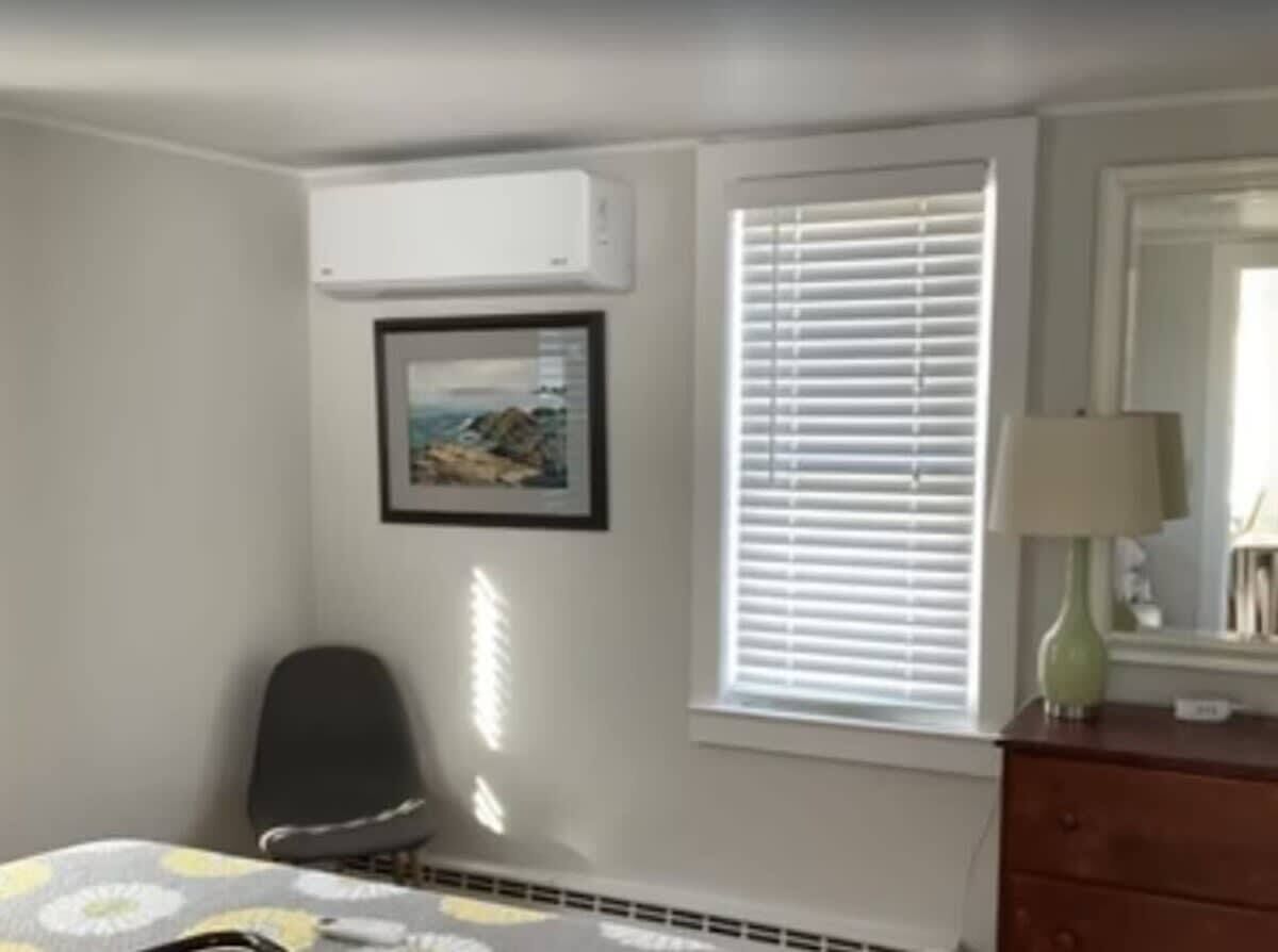 A bedroom with a bed, a chair, a dresser, a window with blinds, and a framed picture on the wall.