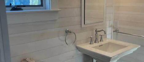 A bathroom with a window, a sink, and a toilet.