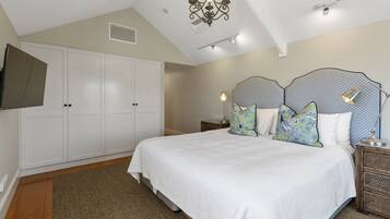 A bedroom with a large bed, white wardrobe, and a TV mounted on the wall.