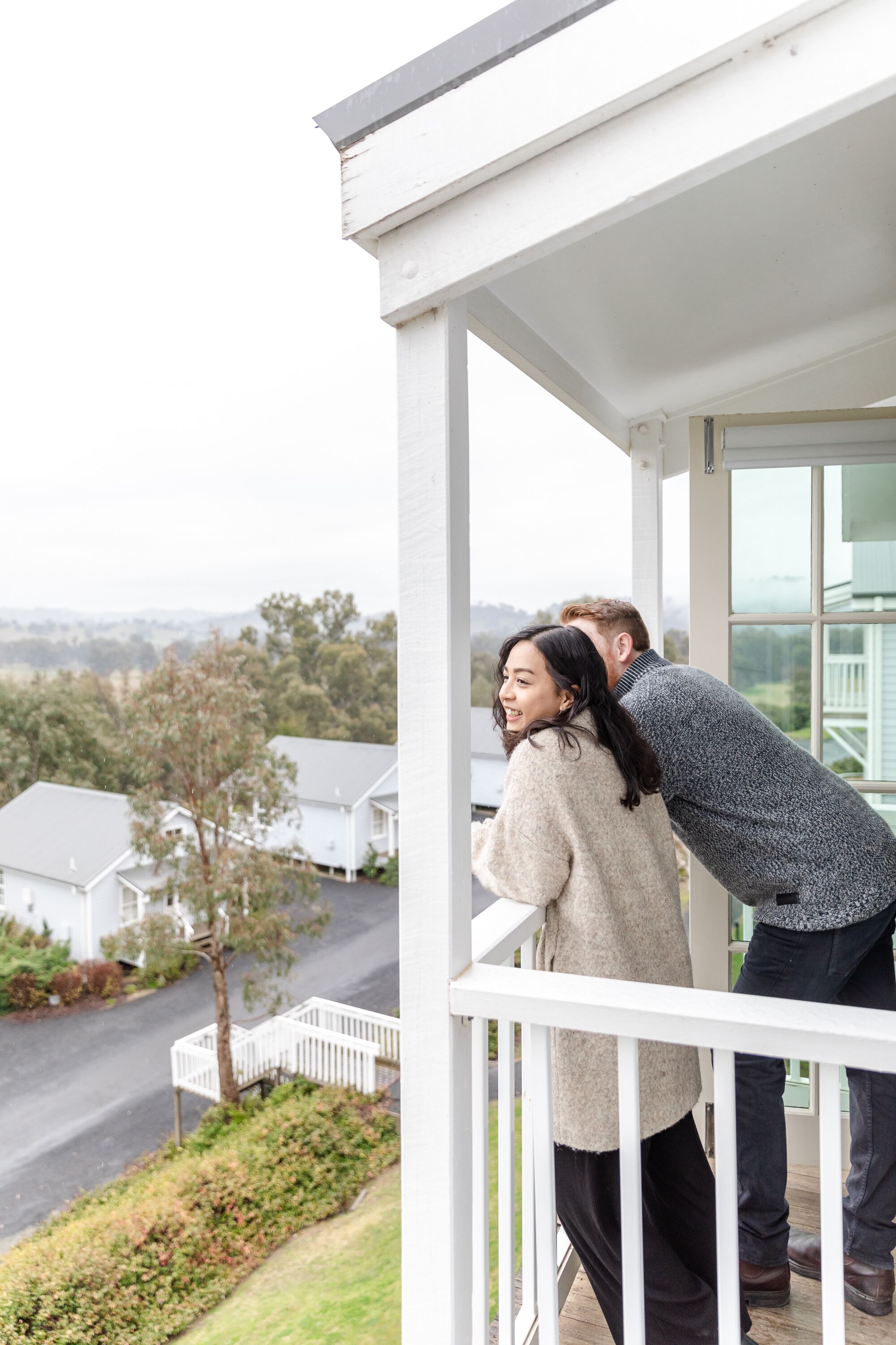 A balcony with a view of houses and greenery.