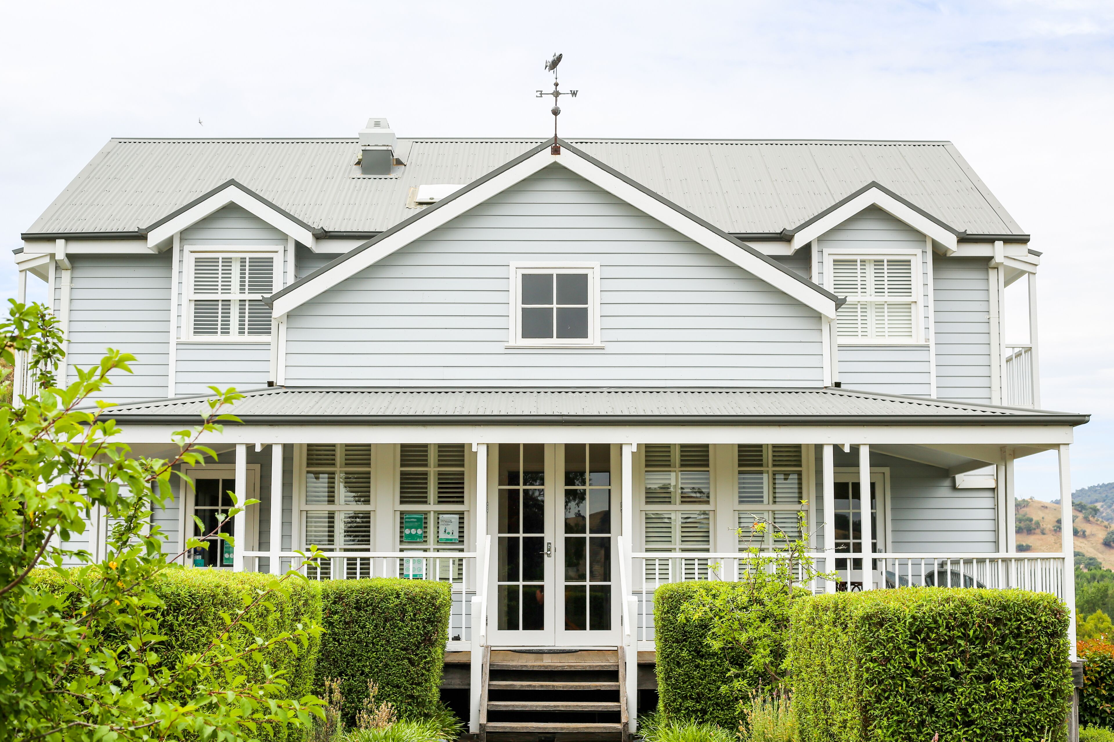 A two-story house with a front porch, a central door, and a small window.
