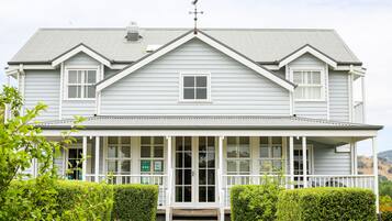 A two-story house with a front porch, a central door, and a small window.