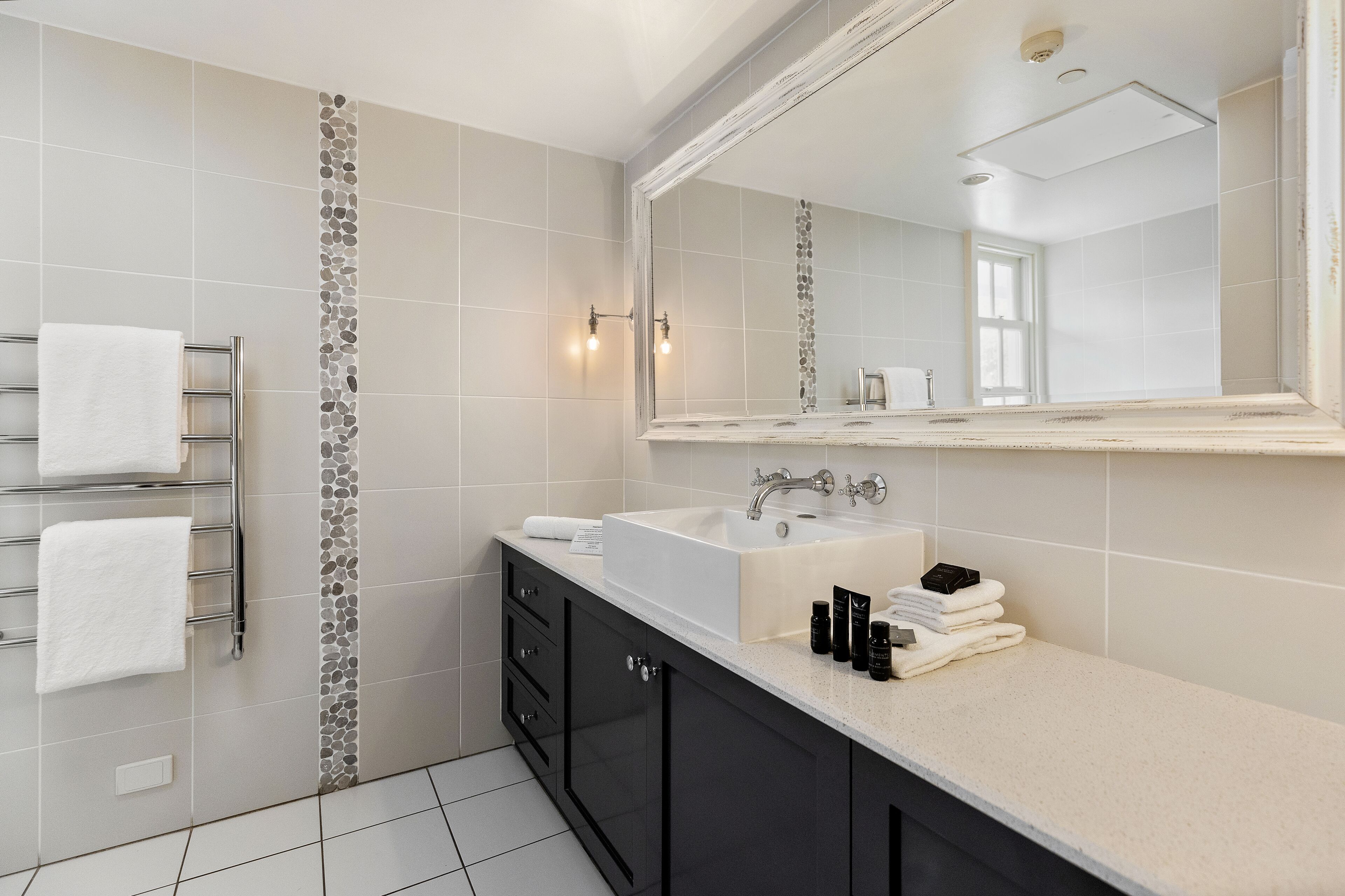 A modern bathroom with a large mirror, a sink, and a towel rack.