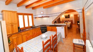 A kitchen with wooden cabinets, a dining table with chairs, and a view into the dining area. - Can Palea, Wi-fi free, private pool, garden, 15 minutes from the beach Es Trenc (Campos)