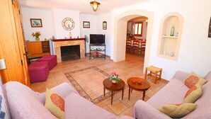 A living room with a fireplace, sofas, a TV, and a dining area with chairs and a table. - Can Palea, Wi-fi free, private pool, garden, 15 minutes from the beach Es Trenc (Campos)