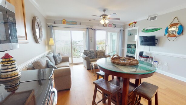 A spacious living area with a glass dining table, a sofa, and a television.