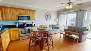 A modern kitchen with wooden cabinets, stainless steel appliances, and a round glass table with stools.