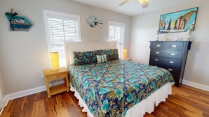 A bedroom with a bed, a nightstand, a dresser, and a painting on the wall.