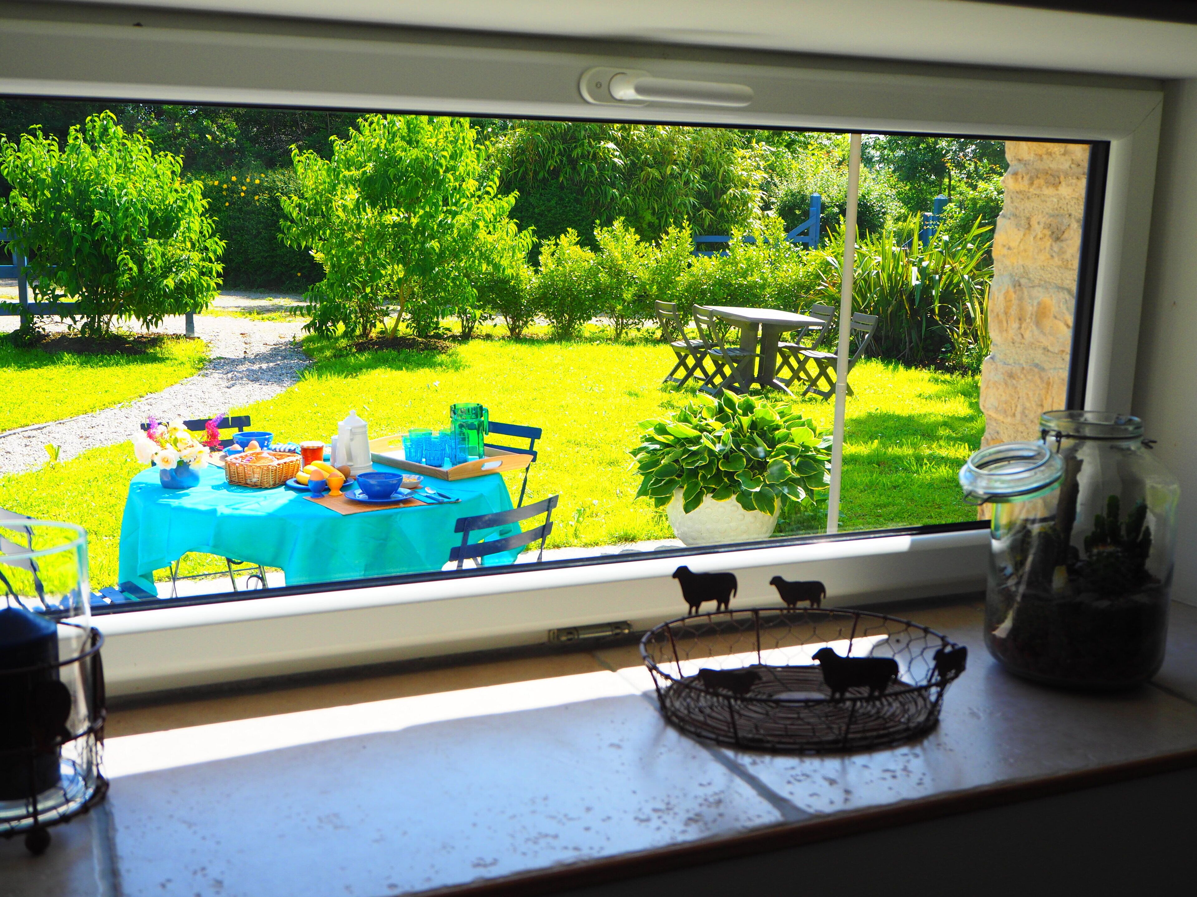 A kitchen window with a view of a backyard patio area.