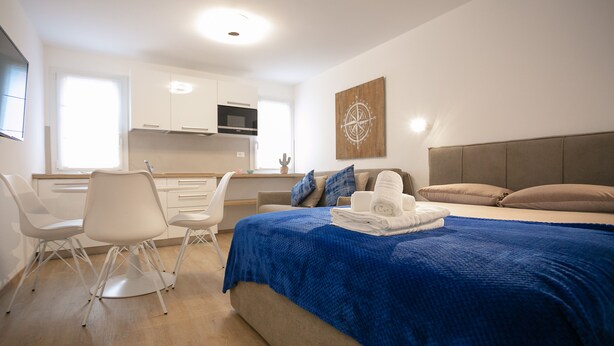 Ein modernes Schlafzimmer mit einem großen Bett, einem Schreibtisch und einer Küchenzeile.