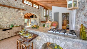 A rustic kitchen with stone walls, wooden beams, and a gas stove. - Lemon Garden Retreat - Exclusive Resort in Lemon Grove with pool for 18 people (gargnano)