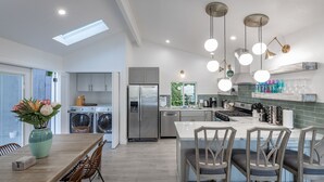 Une cuisine moderne dotée d’un îlot central, de luminaires suspendus et d’une verrière.