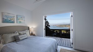Une chambre à coucher avec un lit, des oreillers, une table de chevet et une vue sur un balcon.