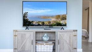 Un téléviseur fixé sur un meuble en bois, avec vue sur un paysage côtier.