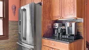 Una cocina con armarios de madera, un refrigerador de acero inoxidable, una cafetera y un microondas sobre la encimera.