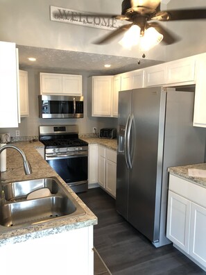 A modern kitchen with white cabinets, stainless steel appliances, and a granite countertop.