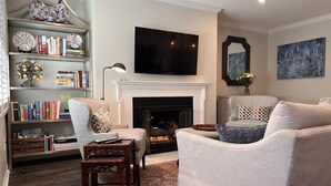 A living room with a fireplace, a television, and a bookshelf filled with books.