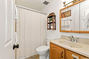 A bathroom with a toilet, sink, mirror, and shower curtain.