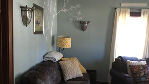 Een woonkamer met een bruine leren bank, een lamp en een muur met een boomdecoratie.