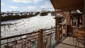 A balcony with a view of a snowy ski slope and a pool area. - Luxury True Ski-in/out slope side condo March 17-24, 2024 Prime Spring Break (Breckenridge)