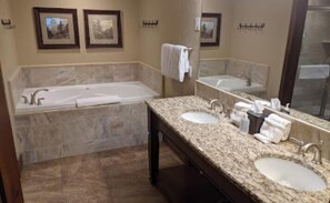 A bathroom with a bathtub, two sinks, and a large mirror.