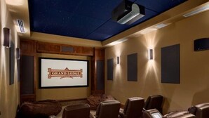 A home theater room with a starry ceiling, a large screen displaying "Grand Lodge," and multiple rows of leather recliner seating. - Luxury True Ski-in/out slope side condo March 17-24, 2024 Prime Spring Break (Breckenridge)