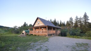 Een houten hut met een veranda, een picknicktafel en een grindpad.