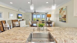A kitchen with a granite countertop, stainless steel sink, and overhead lighting. - 616 Surf Villas, Oceanfront Condo, BAM Vacation Rentals (Ponte Vedra Beach)