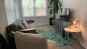 Ein Wohnzimmer mit Sofa, Couchtisch, Fernseher, Pflanze und Lampe.