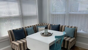Eine Sitzecke mit gestreiften Sofas und einem weißen Tisch, mit einer Laterne und einem Tablett.