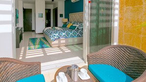 Une chambre à coucher avec un lit, une salle de bain et un balcon aménagé avec des meubles en osier.