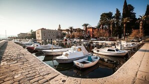 Un port de plaisance avec plusieurs bateaux amarrés, des quais en pierre et des bâtiments en arrière-plan.