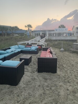 Relax in wicker lounge chairs on the beach, overlooking the ocean with views of THE DECK in the distance.