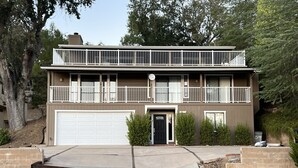 A two-story residential building with a front garage, a balcony on the upper floor, and a landscaped front yard. - Wow! 2 Master Suites, Lake Naci Views, WiFi, and Private Slip! (Lake Nacimiento)