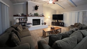 A living room with a fireplace, a ceiling fan, a television, and a large sofa. - Wow! 2 Master Suites, Lake Naci Views, WiFi, and Private Slip! (Lake Nacimiento)