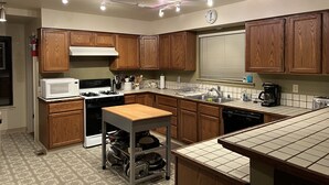 A kitchen with wooden cabinets, a microwave, stove, sink, and a small table with a shelf underneath. - Wow! 2 Master Suites, Lake Naci Views, WiFi, and Private Slip! (Lake Nacimiento)