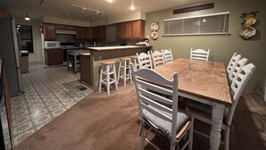 A kitchen with a central island, white bar stools, and a dining table with chairs. - Wow! 2 Master Suites, Lake Naci Views, WiFi, and Private Slip! (Lake Nacimiento)