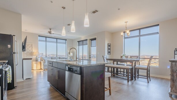 Una cocina moderna con una isla grande, luces colgantes y un comedor con vistas.